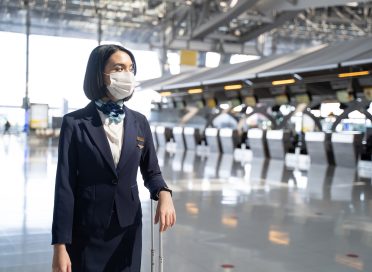 Airliner air hostess crew wearing face mask, walk in airport terminal.