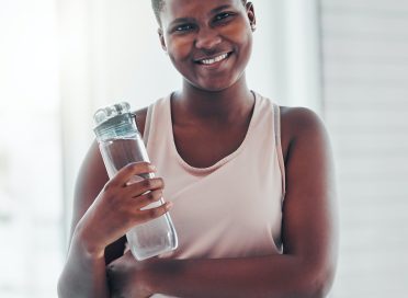 Portrait, black woman and exercise with water bottle, smile and training for wellness, balance or h